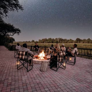 Friends and family sitting around a campfire under the milky way at night