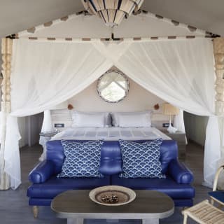 Four-poster kingsize beds in safari tents are protected by hanging mosquito nets