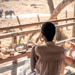 Guests eating breakfast on their private terrace watching elephants in the water just below