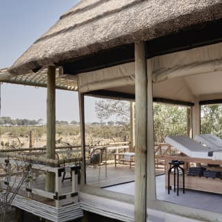 Spa treatment beds under a thatched roof with side walls open to the bush