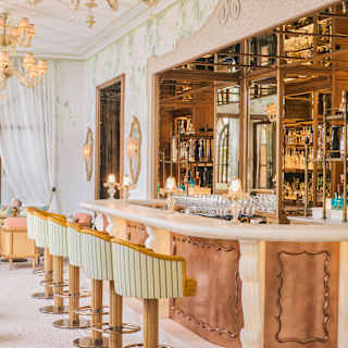 Six tub stools in mint and white stripe line a copper and marble bar in a view that captures a botanical wall mural surround.