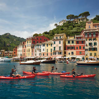 Guests in four vibrant red kayaks sailing across Portofino harbour