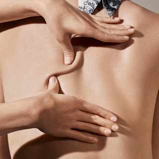 A masseuse's thumbs apply pressure to a guest's back, pulling the skin in different directions, seen in a Spa Dior close-up.