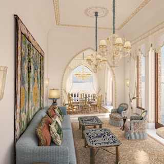 A blue sofa faces a row of full-height windows on to the sea in Villa Beatrice's living room, with adjoining dining room.