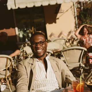 Homme souriant qui boit un cocktail à une table de restaurant en terrasse
