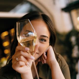 A woman admires white wine in a long-stem glass