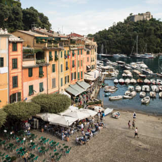Pastel town houses lining Portofino shore and boats anchored in the harbour