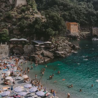 Swimmers gather in the turquoise waters of Bagni Fiore. Beach dwellers rest in the sun or shaded by lavender parasols