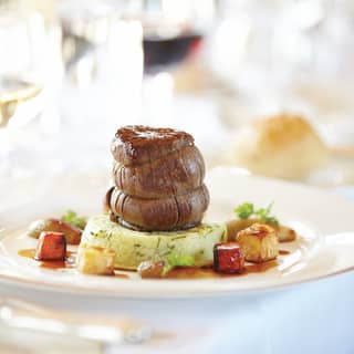 Close-up of Aberdeen Angus beef stacked on a herb mash surrounded by vegetables
