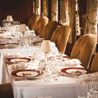 Formal place settings on tables-for-four surrounded by sage velvet dining chairs