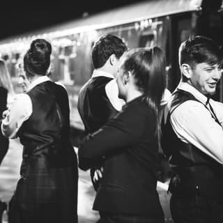 A party of guests ceilidh dancing on a train platform