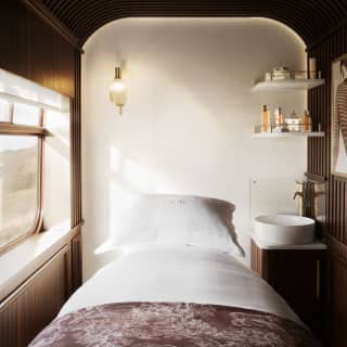 Inside a serene Dior Spa treatment room, with a fresh white bed, sink and shelves of products, cocooned in cedar panelling.