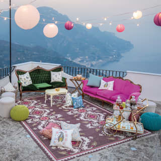 The rooftop terrace is prepared with sofas, drinks and twinkling lights, ready for a celebration in the dusky Amalfi evening.