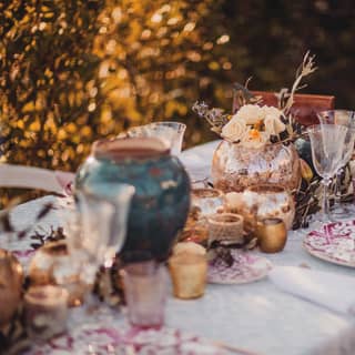 Garden blooms adorn the outside table, set with an eclectic mix of pink china, golden tealights, wine flutes and water jugs.