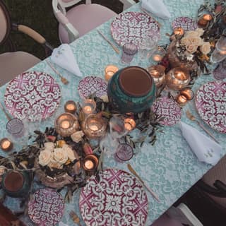 Aerial view of a table laid with peppermint cloth, pink and white china, glowing tealights and blooms for a special occasion.