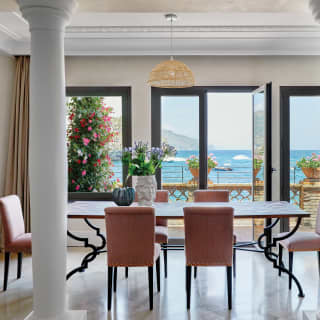 Hotel suite dining area next to white columns, with black and terracotta accents