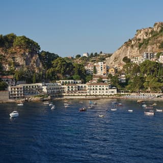 Villa Sant'Andrea looks resplendent in this view from the sea, its white facade echoing the white limestone cliffs around it