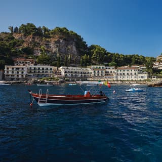 Boats bobbing in Taormina bay with grand residences lining the shore
