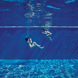 Endless blue creates a stunning playground for two children as they sink below the surface of their swimming pool