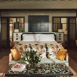 Sunlight brushes the botanic-print sofa and coffee table in view of a garden-theme Junior Suite with a bench, bed and desk.