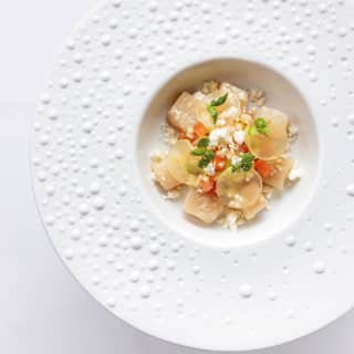 Birds-eye-view of a ravioli dish topped with parmesan in a wide-brimmed white bowl