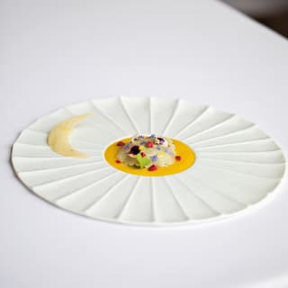 Close-up of a white sun-shaped dish of oysters with camomile, bergamot and petals by La Loggia Chef Alessandro Cozzolino.