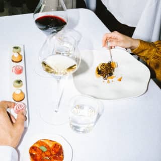 Two guests enjoy the tasting menu, with amuse-bouches in swirls and bites of vibrant hues, and plates of crafted appetisers.