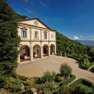 Classical exterior of a former Italian monastery with arched cloisters and a grand drive