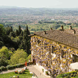 High-angle view over the tiled roofs, wisteria-clad walls and gardens of Villa San Michele, extending beyond to Firenze.