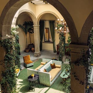 Aerial view of an atrium guest area with foliage-covered columns and soft velvet furnishings