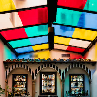 View of the bar area with a glass roof providing MITICO's canvas, installed with block panels of red, green, blue and yellow.
