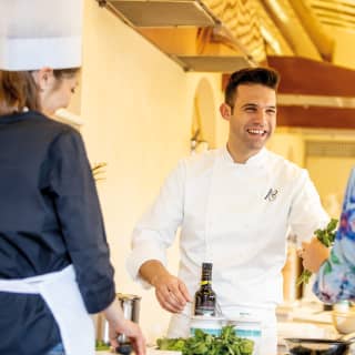 Executive chef, Alessandro Cozzolino, smiles as he hands a bunch of fresh basil to a woman during a cookery demonstration