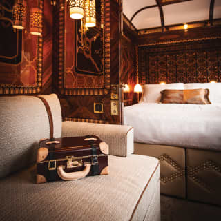 Glamorous train cabin suite with king-size bed, ornate marquetry and plush sofa