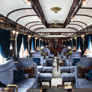 Train bar car with blue velvet banquette seating and blush coloured table lamps