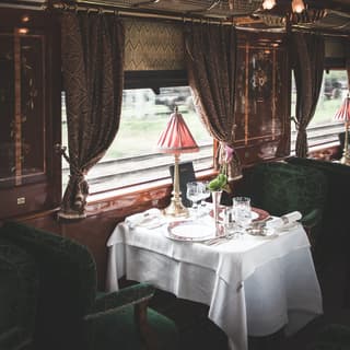 Vintage train dining car with French-polished wood panels and green velvet chairs