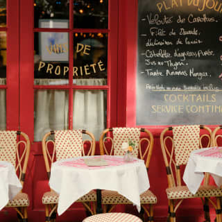 Round tables and cane bistro chairs line the rouge-framed windows and chalk board outside La Mère Catherine in Monmartre.