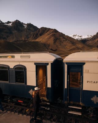 A lady boarding the Andean Explorer train in the sunset