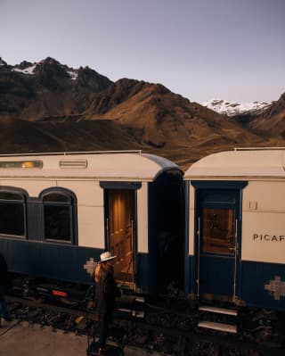 A woman in a fedora hat stepping in the carriage of the Andean Explorer