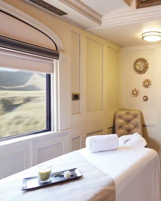 Bright train spa carriage with a massage table next to a large picture window