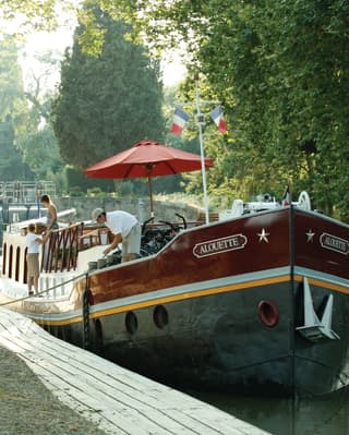 Barcaça de luxo ancorada em um canal arborizado
