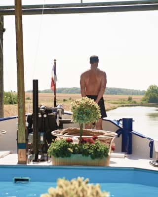 Guest standing on the bow of a luxury barge looking out at the French countryside