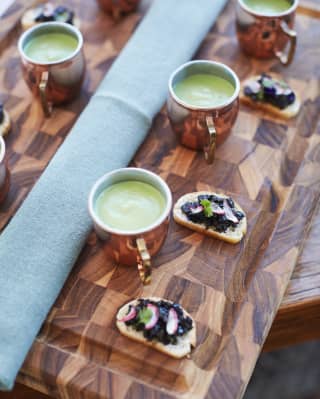close up of a small cups of soup and canapés