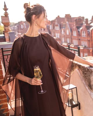 A lady holding a glass of champagne looking out from a suite balcony
