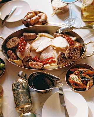 A festive feast of roast turkey with carrots, parsnips, sprouts and gravy, enjoyed with Christmas crackers, seen from above.