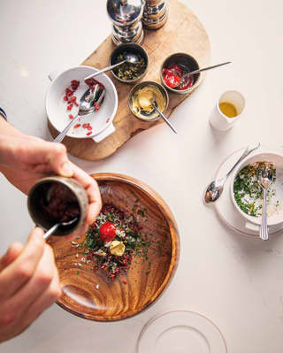 Birds eye view of a hand mixing salad with a collection of seasoning pots