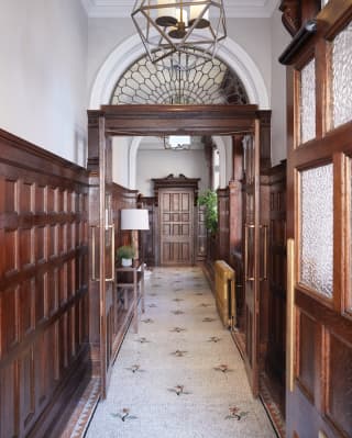 Double-height corridor with gleaming dark wood panelled walls and mosaic floor