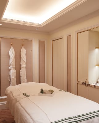Spa treatment room with dusky pink panelled walls and hanging bathrobes