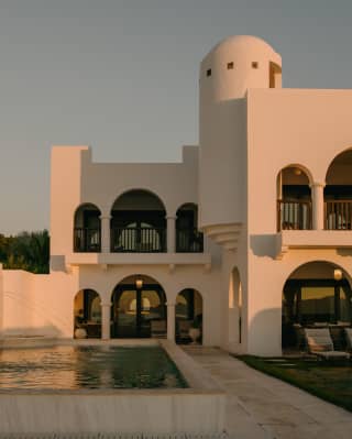 The white Greco-Moorish domes and arches of the Jonquil Suite glow in rose sunlight, which brushes the surface of the pool.