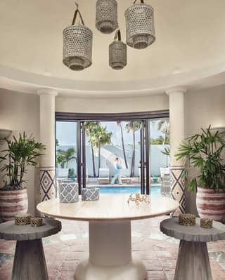 Circular spa entrance hall lined by potted palms and leading to a pool
