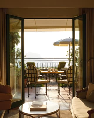 Balcony view through French doors with a parasol and chairs 